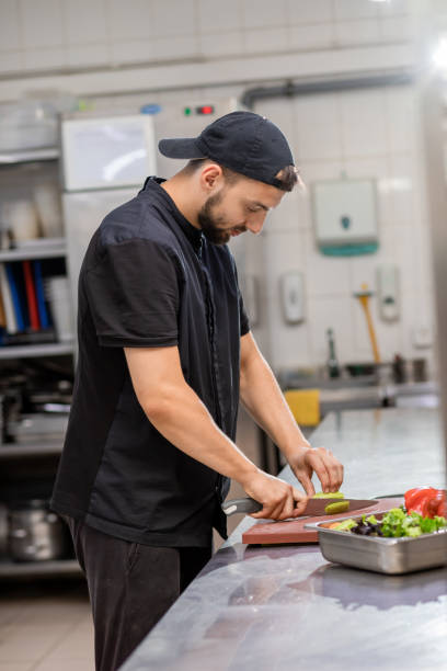 istock Professional smiling chef in uniform cut fresh vegetables in kitchen. Cook man cooking delicious garnish for clients in restaurant. Culinary concept 1456018062
