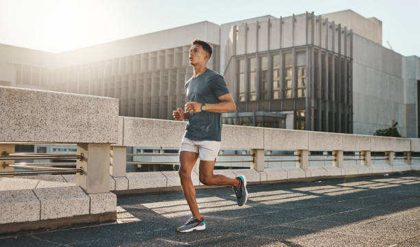 fitness, salud y hombre de ciudad corriendo en la calle con motivación, mentalidad saludable y energía matutina de verano para entrenar. entrenamiento urbano, ejercicio cardiovascular y corredor en bridge, se centran en el estilo de vida deportivo. - pruebas en pista fotografías e imágenes de stock