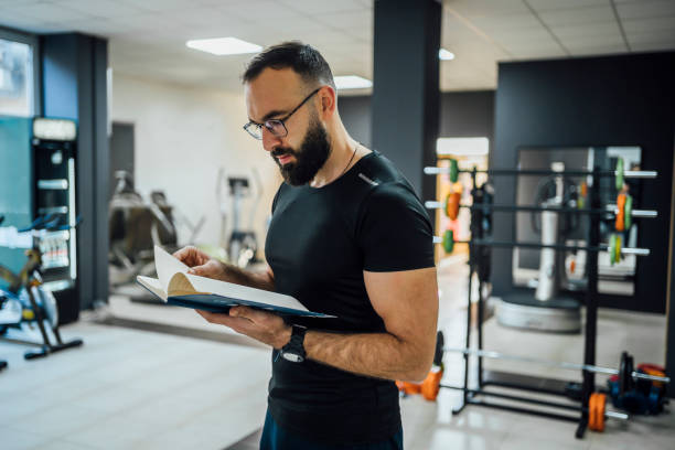 Male fitness trainer reading schedule stock photo