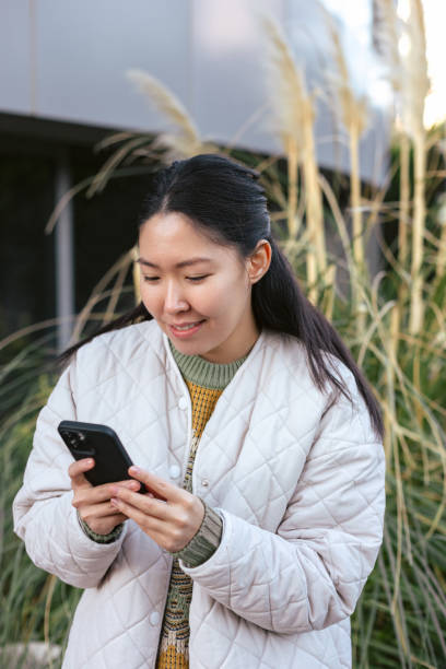 istock Young asian woman using smart phone outside 1456019734