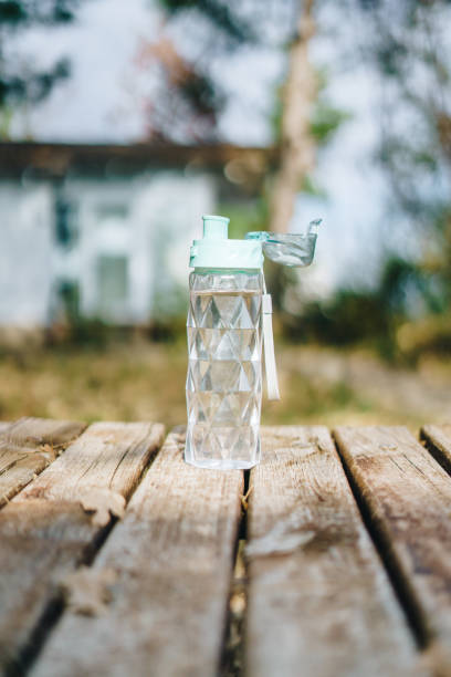 istock Plastic reusable water bottle on a wooden table outdoors 1456020365