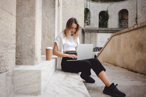 istock Self employed woman working with laptop while sitting on the downstairs. 1456021528
