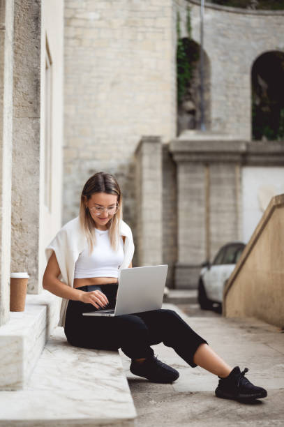 istock woman working on laptop while sitting on steps  in Italy. 1456021574