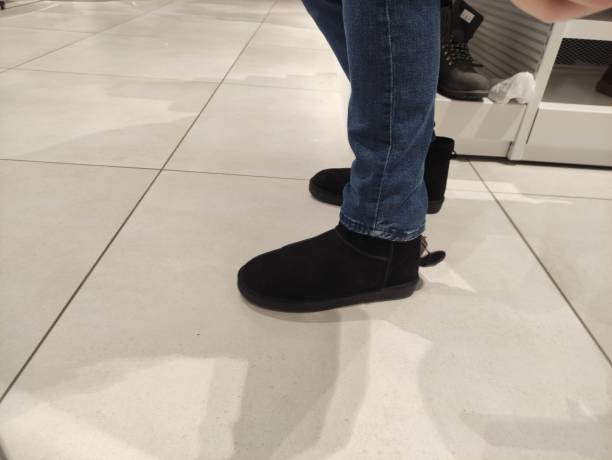 istock Man trying on black winter boots in a store 1456023060