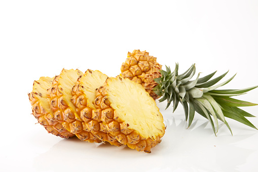 Pineapple fruit with cut slices isolated on white background. Top view. Flat lay.