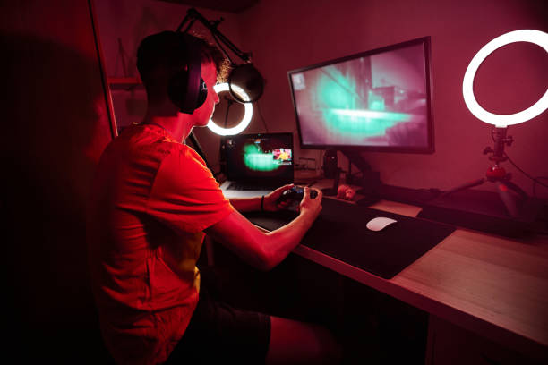 istock Gamer playing with a console and a computer screen indoors 1456023166