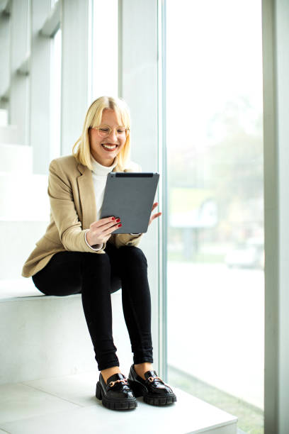 Young blond female businesswoman  working on a digital tablet inside modern building stock photo