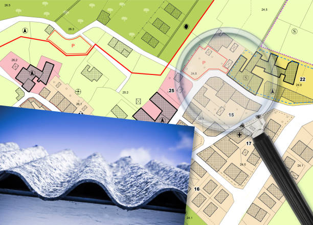 istock Mapping roofing with asbestos-containing material - concept with a magnifying glass against an imaginary city map 1456026937