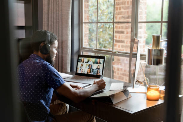 Young adult college student takes notes for online class stock photo