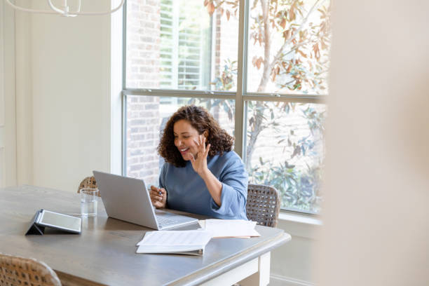 istock Woman waves as she gets online for continuing ed course 1456028752