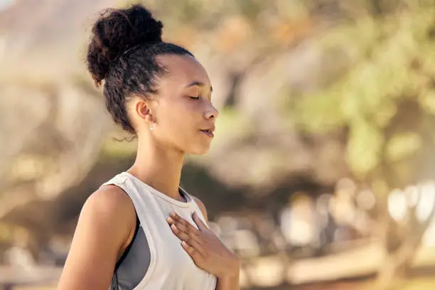 Photo of Black woman, breath and hand on chest, for meditation and wellness being peaceful to relax. Bokeh, African American female and lady outdoor, in nature and being calm for breathing exercise and health