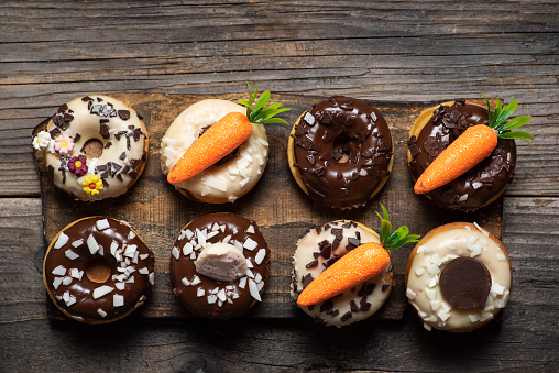 Mini donuts with white and dark chocolate and Easter decoration on rustic wooden background