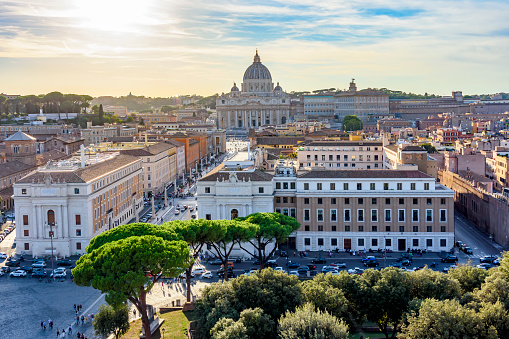 A suggestive view over the rooftops of Rome from the panoramic terrace of the Aventine hill, in the historic heart of the Eternal City. On the horizon the iconic and majestic dome of the Basilica of Saint Peter's, while in foreground the Trastevere district. The Aventine, one of the seven historical hills of Rome, is one of the most visited places in the city due to the presence of tree-lined gardens, archaeological sites from the Roman era and some of the oldest churches in Rome from the Byzantine and medieval eras. In 1980 the historic center of Rome was declared a World Heritage Site by Unesco. Image in 16:9 and high definition format.