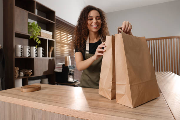 istock Worker with paper bags at counter in cafe, focus on hands 1456038164