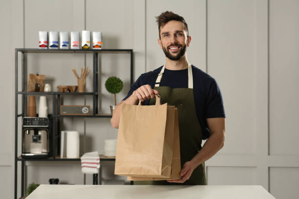 istock Worker with paper bags at counter in cafe 1456038180