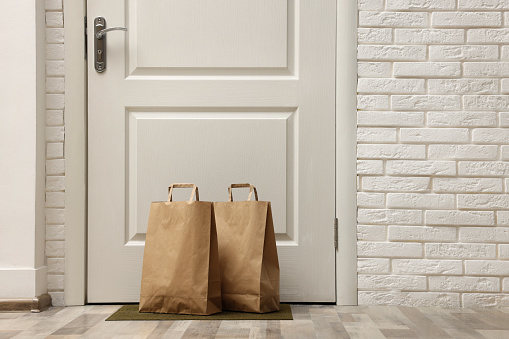 Paper bags on door mat near entrance, space for text