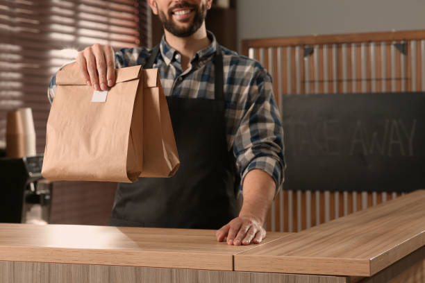 istock Worker with paper bags at counter in cafe, closeup 1456038383