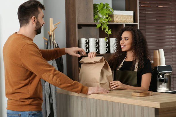 istock Worker giving paper bag to customer in cafe 1456038445