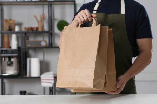 istock Worker with paper bags at counter in cafe, closeup. Space for text 1456039234