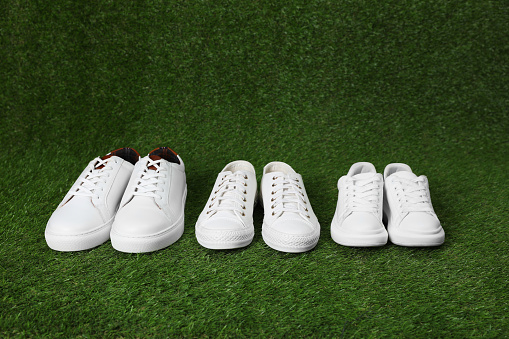 Stylish sports shoes for all family members on green grass