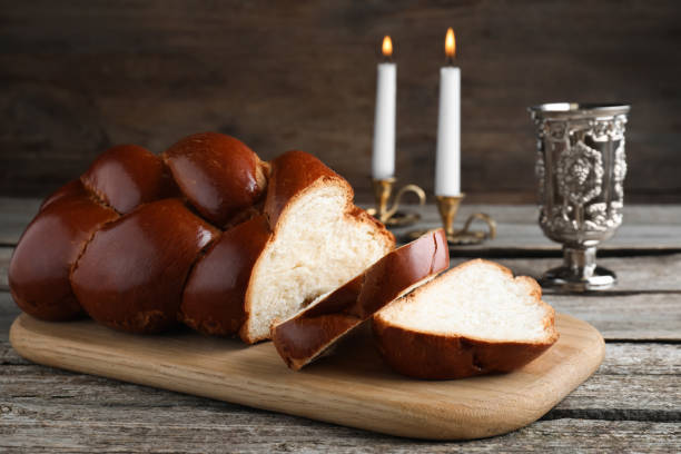 coupez du pain tressé maison, un gobelet et des bougies sur une table en bois. chabat challah traditionnelle - challah jewish sabbath photography candle photos et images de collection