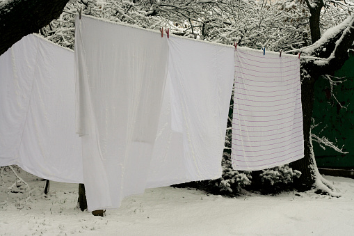 white bed linen drying outdoors on clothesline in snowy winter