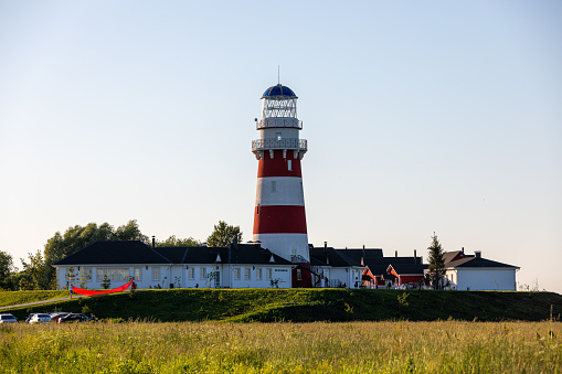 Lighthouse in red and white colors on the seashore, river bank or lake shore. Lighthouse hotel in a fishing village. Travel and tourism concept. Russia, Ryazan region, near the village Shumash. High quality photo