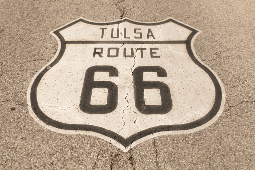 A brown and white road sign of the historic Route 66 on asphalt.