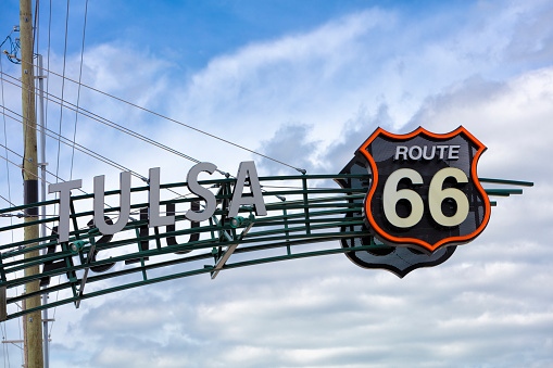 A black and white road sign of the historic Route 66 against blue sky.
