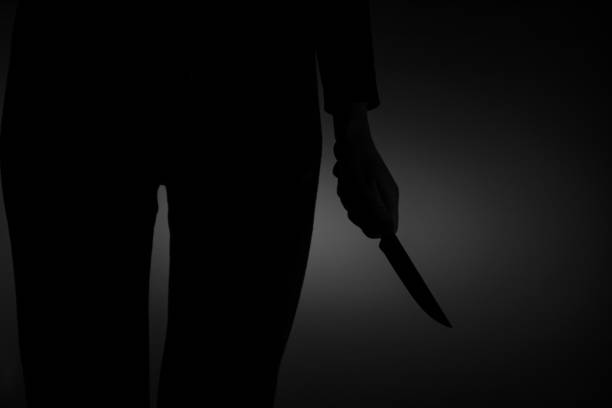 A woman's hand holds a knife in the dark, violence, danger, weapons, harm