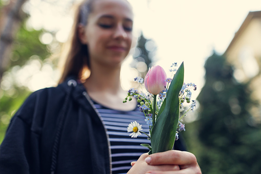 Portrait of a teenage girl holding a bouquet of flowers picked up in the backyard.
Shot with Canon R5