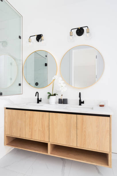 istock A bathroom with a wood cabinet and gold circular mirrors. 1456054585