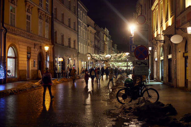 les gens marchent la nuit le long de la rue florianska dans le centre-ville de la ville de cracovie, en pologne. nous voyons la décoration de noël de la rue. - florianska street photos et images de collection