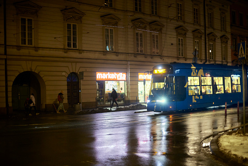Tramway in the evening in Krakow with illuminated windows. Polish architecture, light of lanterns and reflections.
