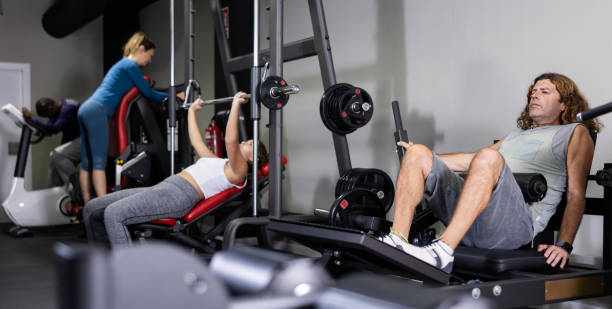 istock Men and women training on machines in gym 1456057844
