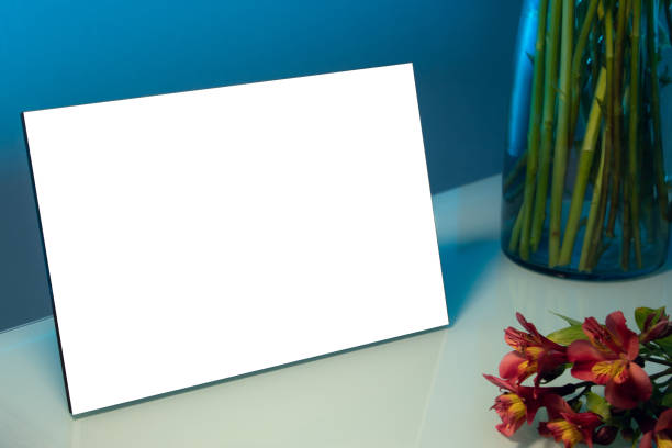 istock A blank photo frame next to a vase and some flowers on a table inside a room at night 1456058639