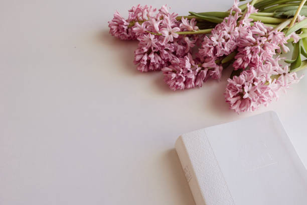 White Holy Christian bible with a bouquet of pink hyacinth flowers on a white background with copy space