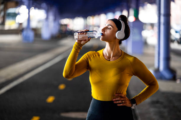 une femme buvant de l’eau pendant une activité physique à new york - east river audio photos et images de collection