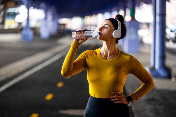 a woman drinking water during fitness activity in new york city - east river audio imagens e fotografias de stock