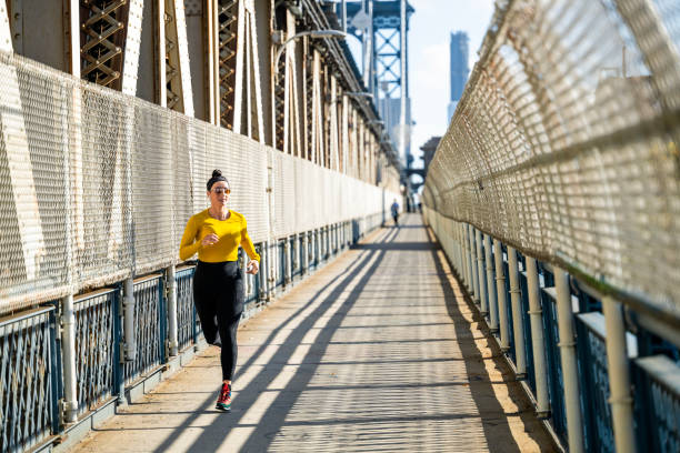 une femme en forme profite de sa séance de course régulière à new york - east river audio photos et images de collection