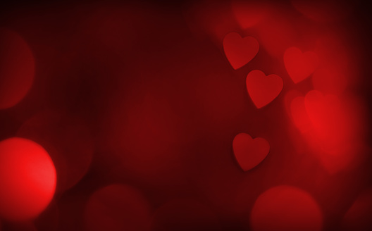 Red defocused bokeh background with heart shape and space for your text. Can be used as a template for romantic, Valentine's day holiday greeting cards or posters.
