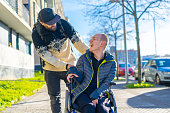 A disabled person in a wheelchair with a friend smiling, handicapped normality