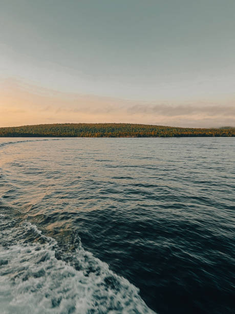 Gliding through the deep blue lake water, taking off from Copper Harbor at the Northern shore of the Upper Peninsula of Michigan Out of this world views looking out over the vast Lake Superior waters as a ferry boat leaves the shores of Copper Harbor, located in the Upper Peninsula of Michigan. Views of the boats wake as it glides through the water, as well as evergreen trees in their pristine natural and untouched environment. sea wake stock pictures, royalty-free photos & images
