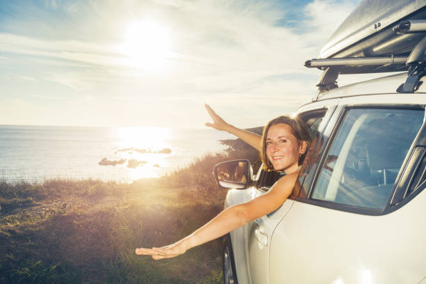 istock Woman smile look from car window on ocean sunset and wave hands 1456068085