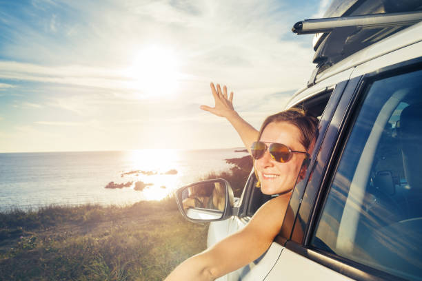 istock Woman on ocean parking wave hands from car window smiling 1456068089