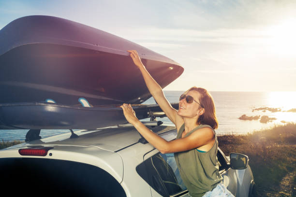 Young woman in sunglasses unload car roof top baggage stock photo
