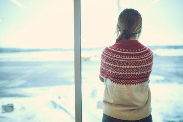 mentre aspetta un volo, una donna guarda gli spazzaneve pulire la neve - rear view winter blizzard nordic countries foto e immagini stock