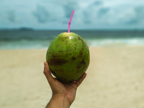 Hand holding a coconut on the beach rio de Janeiro