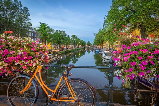 A scenic view of a beautiful canal and a bicycle on a bridge in Amsterdam