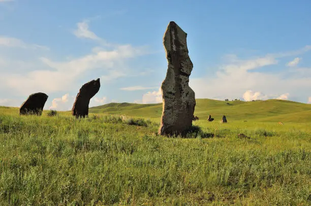 Photo of A group of ancient burial stones on the slopes of a hilly valley on a sunny summer day.